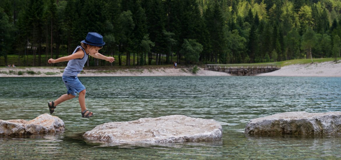 Boy crossing river stepping stones