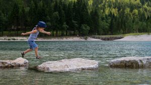 Boy crossing river stepping stones